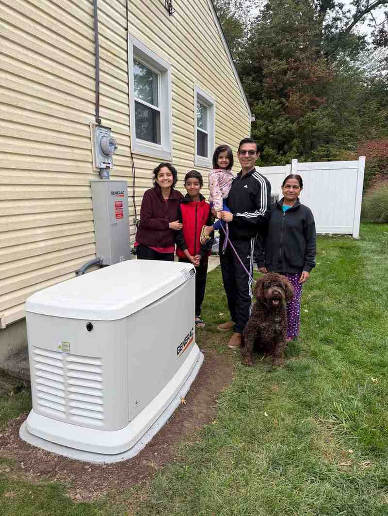 Family with a dog beside a Generac generator installed for home backup power in Blairstown, NJ