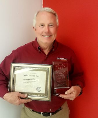 Seidel Electric Inc. representative holding up awards given to the generator services company in Blairstown, NJ